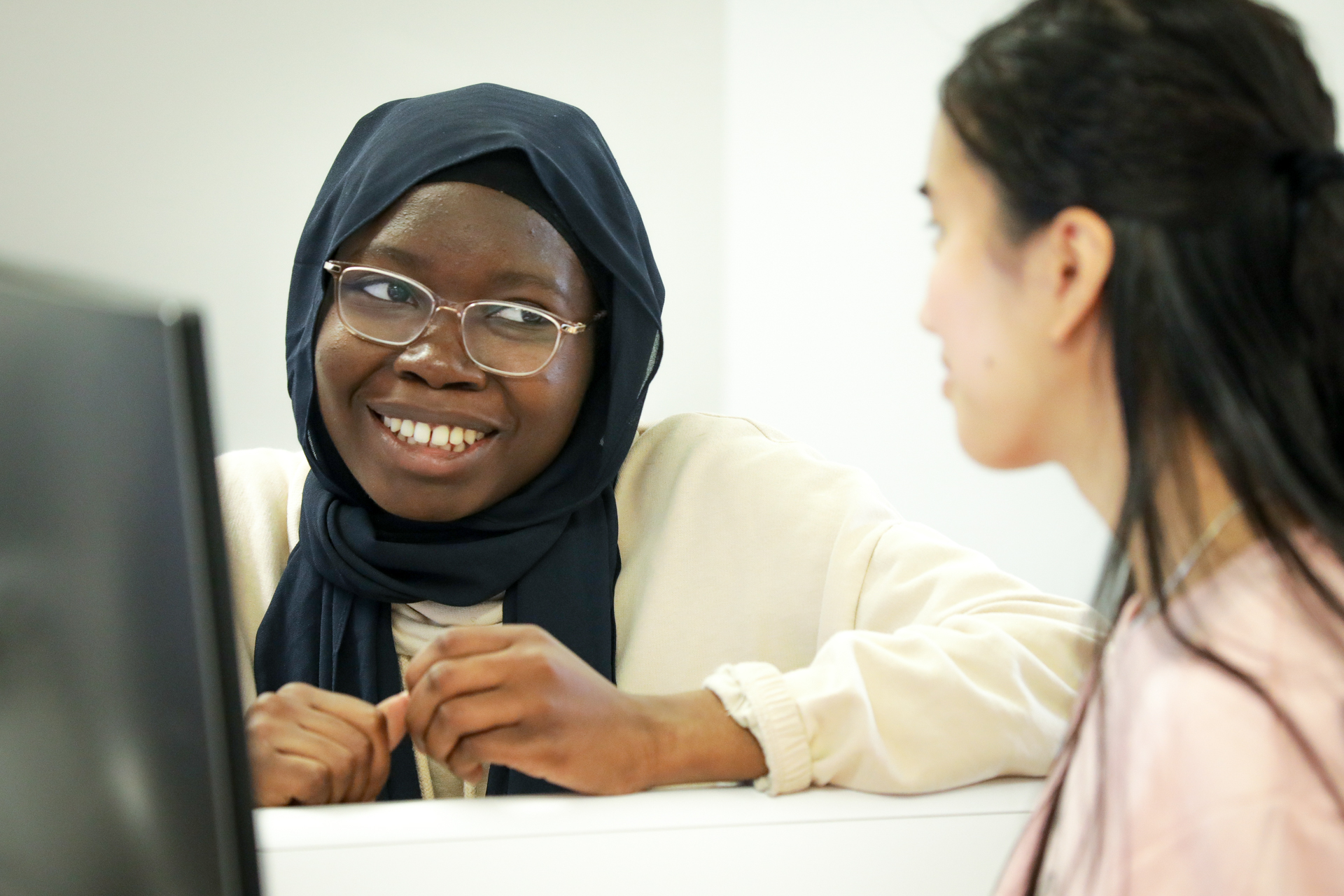 Two students are seated at a desk, collaborating on a computing task.