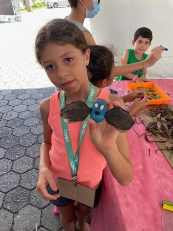 A girl holds up a winged creature she has grafted.