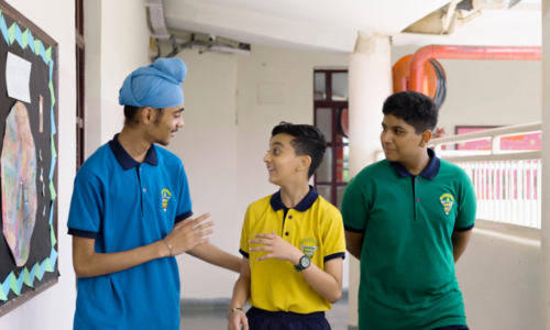 Three students chat outside a school building.