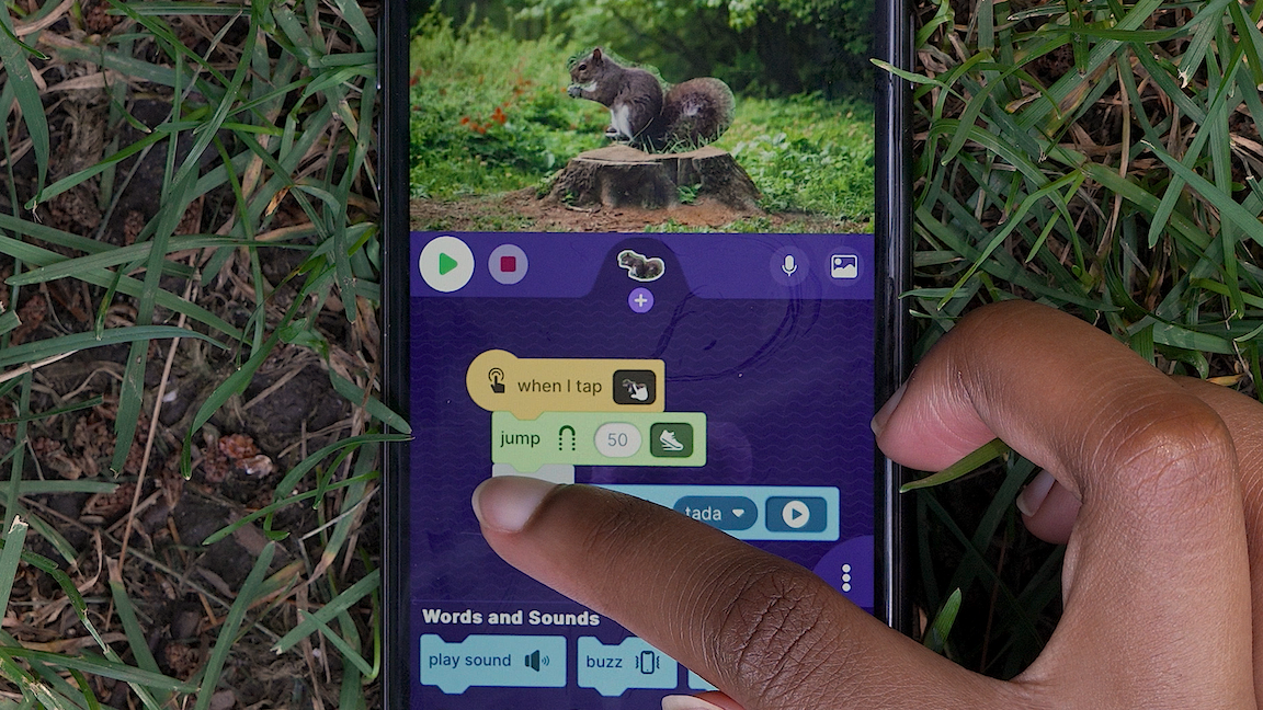 A young person connects coding blocks in their OctoStudio phone app.